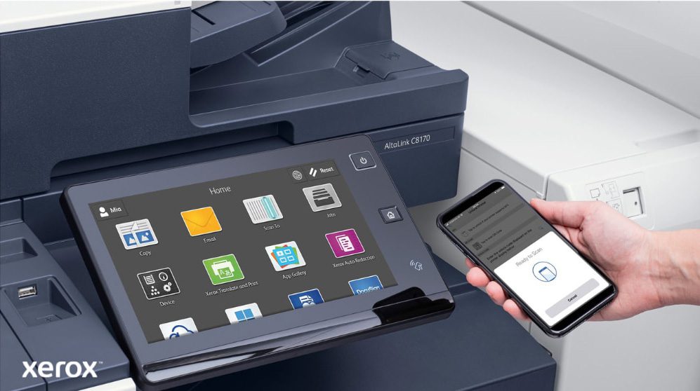Xerox® ConnectKey®: Impresión y escaneo móviles Un primer plano de la mano de una persona que sostiene un teléfono inteligente, que está conectado de forma inalámbrica al panel de control de pantalla táctil de una impresora multifunción Xerox, mostrando las capacidades de impresión y escaneo móviles perfectas de Xerox ConnectKey.