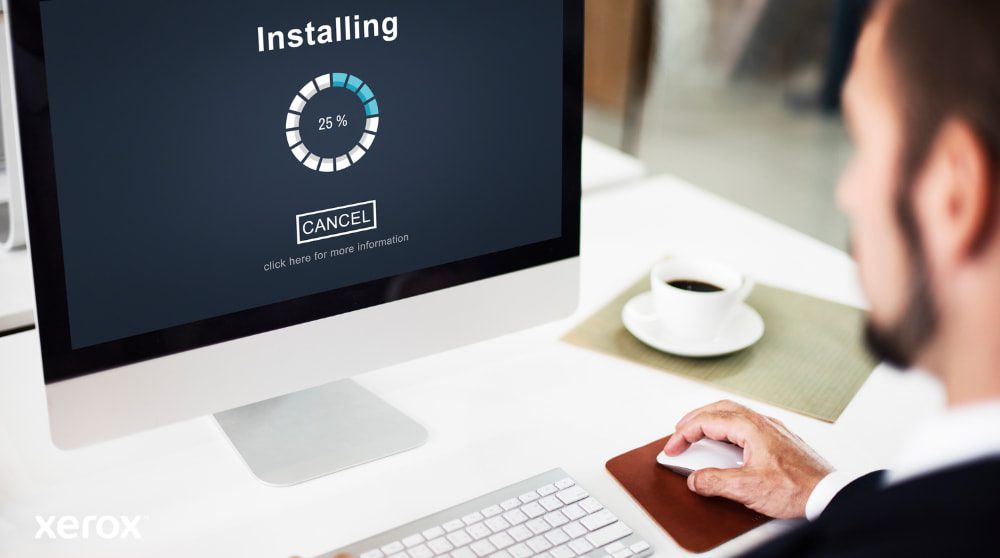 Xerox® Smart Start: Instalación sencilla y rápida Una vista de cerca de un monitor de computadora que muestra una barra de progreso de "Instalación" al 25%, con la mano de una persona sobre un mouse de computadora al lado de una taza de café, lo que ilustra una fácil configuración del software.