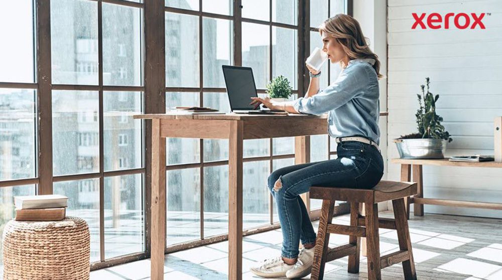 Una mujer sentada en un escritorio, utilizando una computadora portátil, demostrando concentración y productividad.