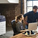 Un hombre y una mujer están uno al lado del otro frente a una computadora, concentrados en la pantalla. La impresora a color Xerox® VersaLink® C7000 está en el fondo. Un hombre y una mujer están uno al lado del otro frente a una computadora, concentrados en la pantalla. La impresora a color Xerox® VersaLink® C7000 está en el fondo.
