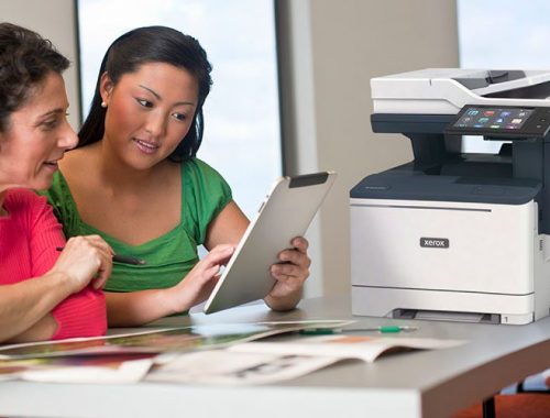 Dos mujeres usando una tableta frente a una impresora multifuncional Xerox® VersaLink® B415